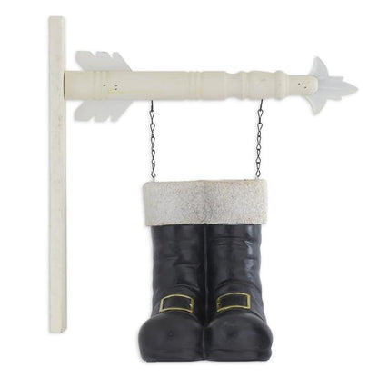 Pair of black resin Santa boots with white fur trim hanging from a white arrow sign post