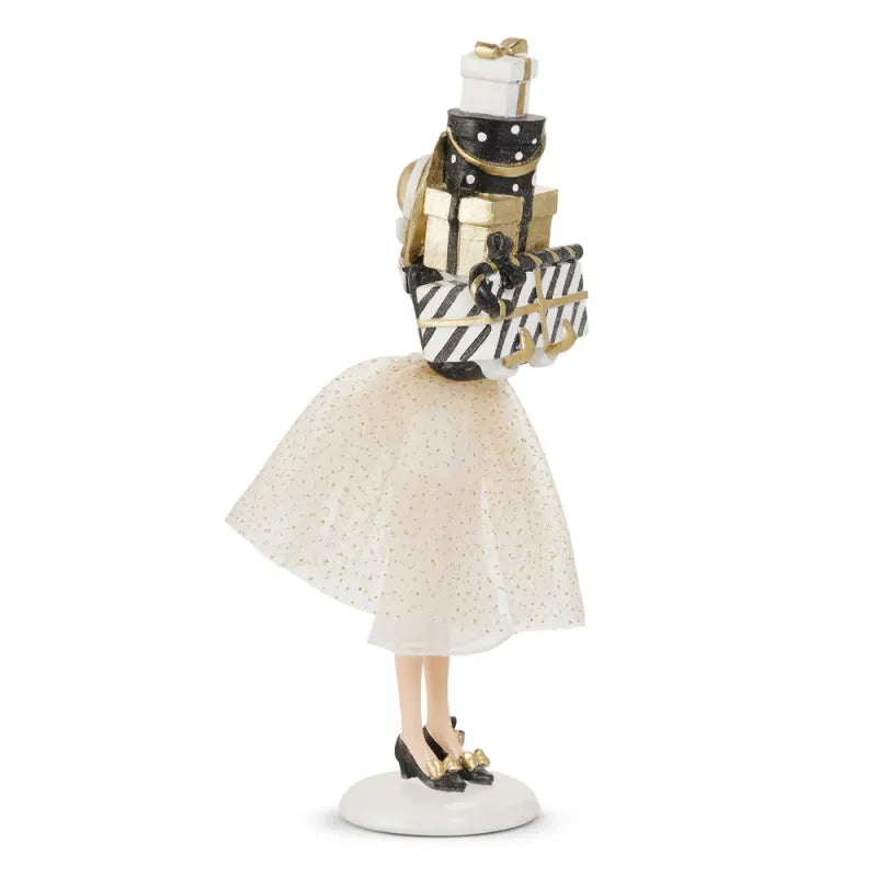 Holiday figurine of woman in tulle skirt carrying tall stack of wrapped gift boxes, side view