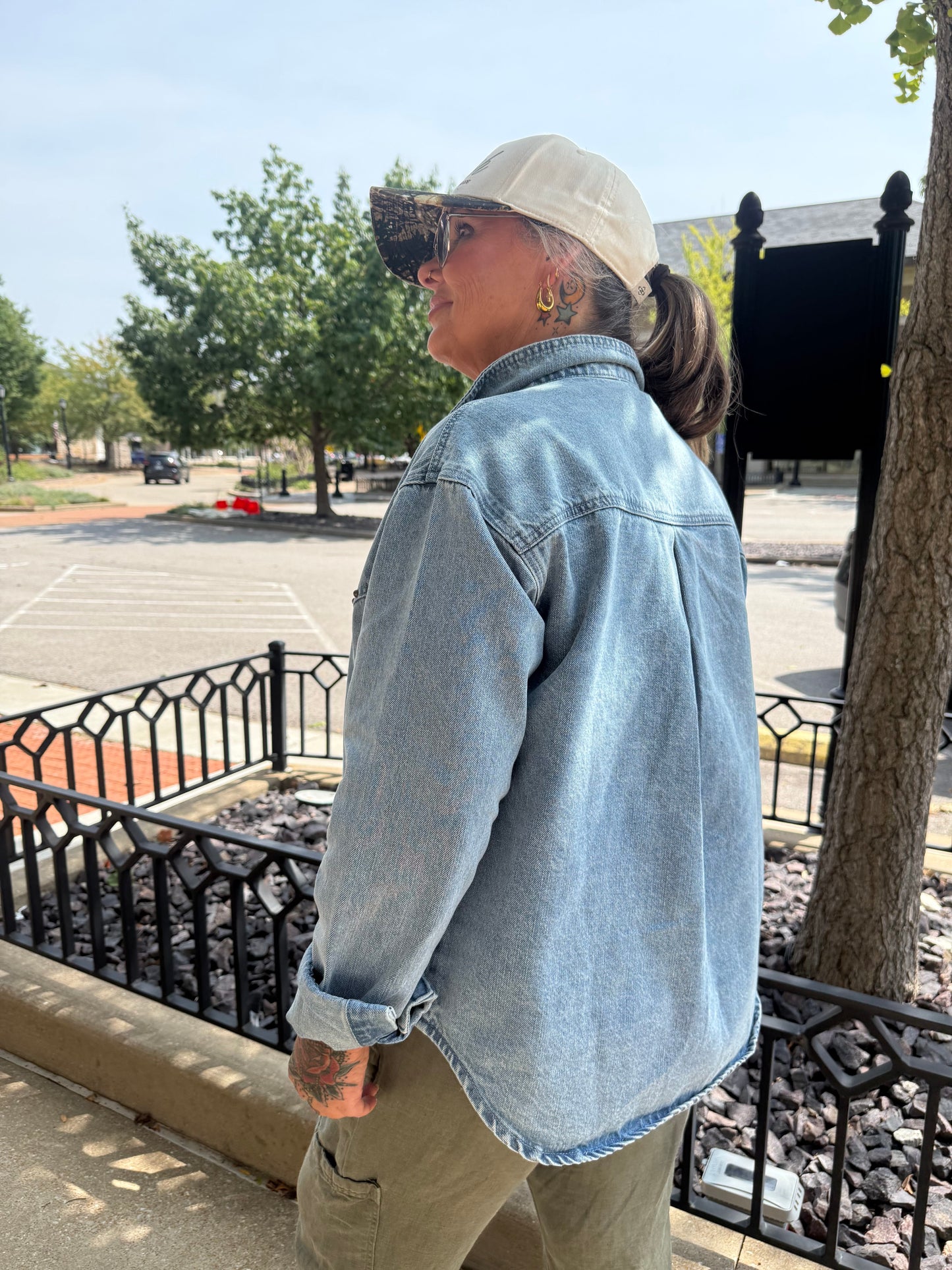 Light wash oversized denim shirt jacket with rolled cuffs, worn casually outdoors