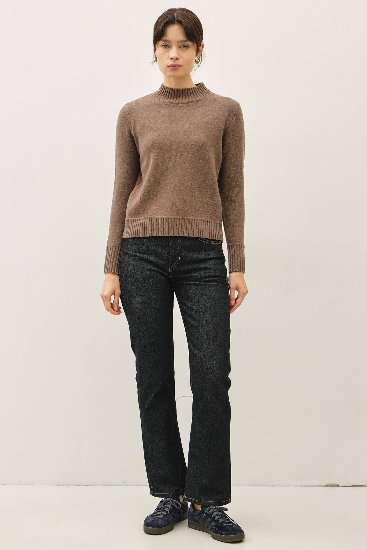 Taupe mockneck sweater with ribbed hem and cuffs, paired with dark jeans