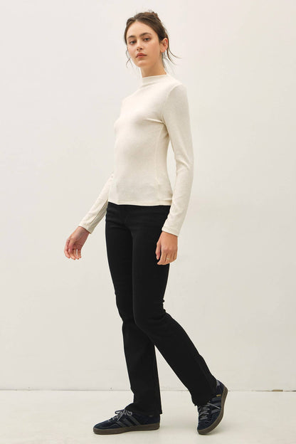 Cream long-sleeve ribbed mockneck fitted knit top paired with black pants