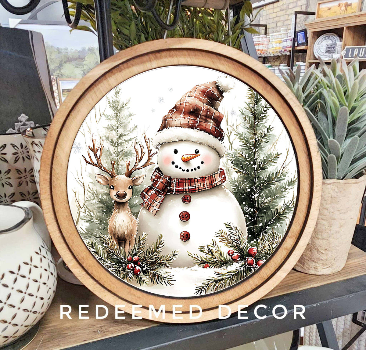 Round wood-framed canvas sign with snowman, reindeer, and plaid accents, 8 inch