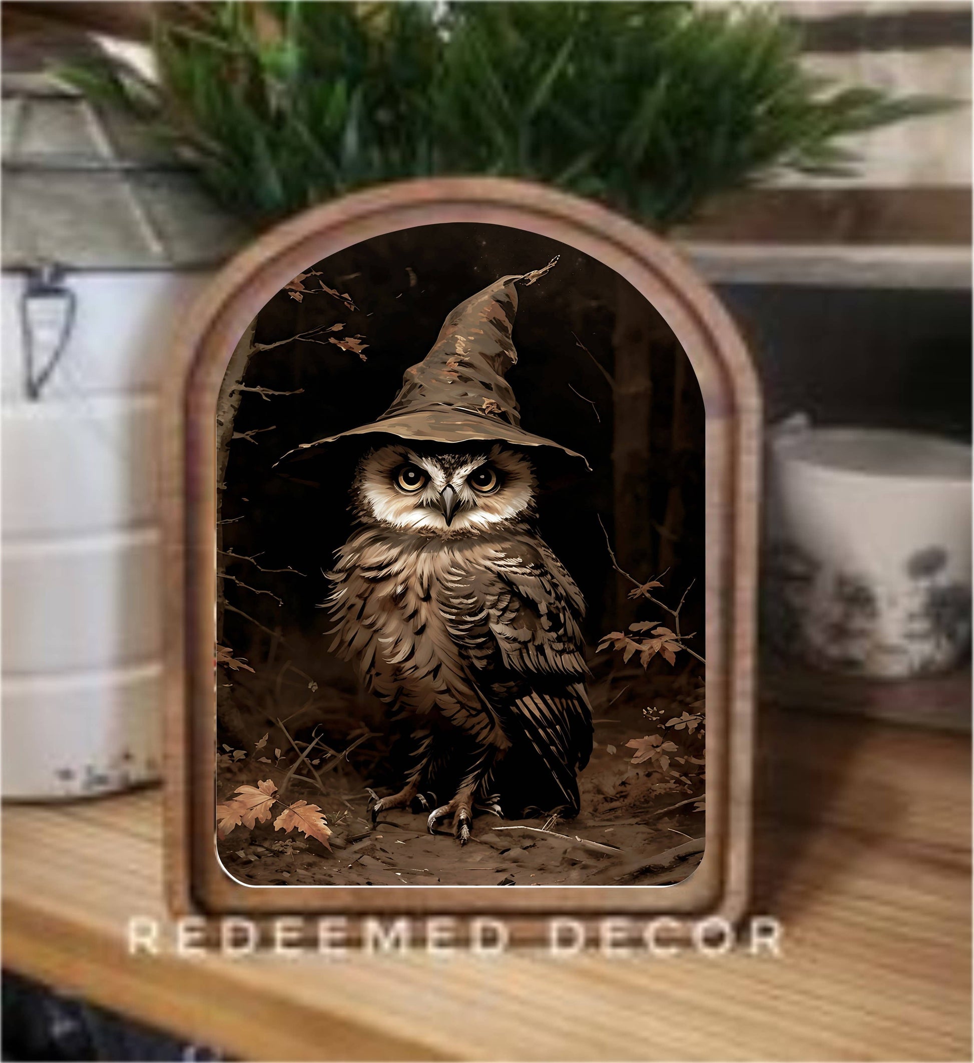 Arched wood-framed canvas art featuring an owl wearing a witch hat among autumn leaves