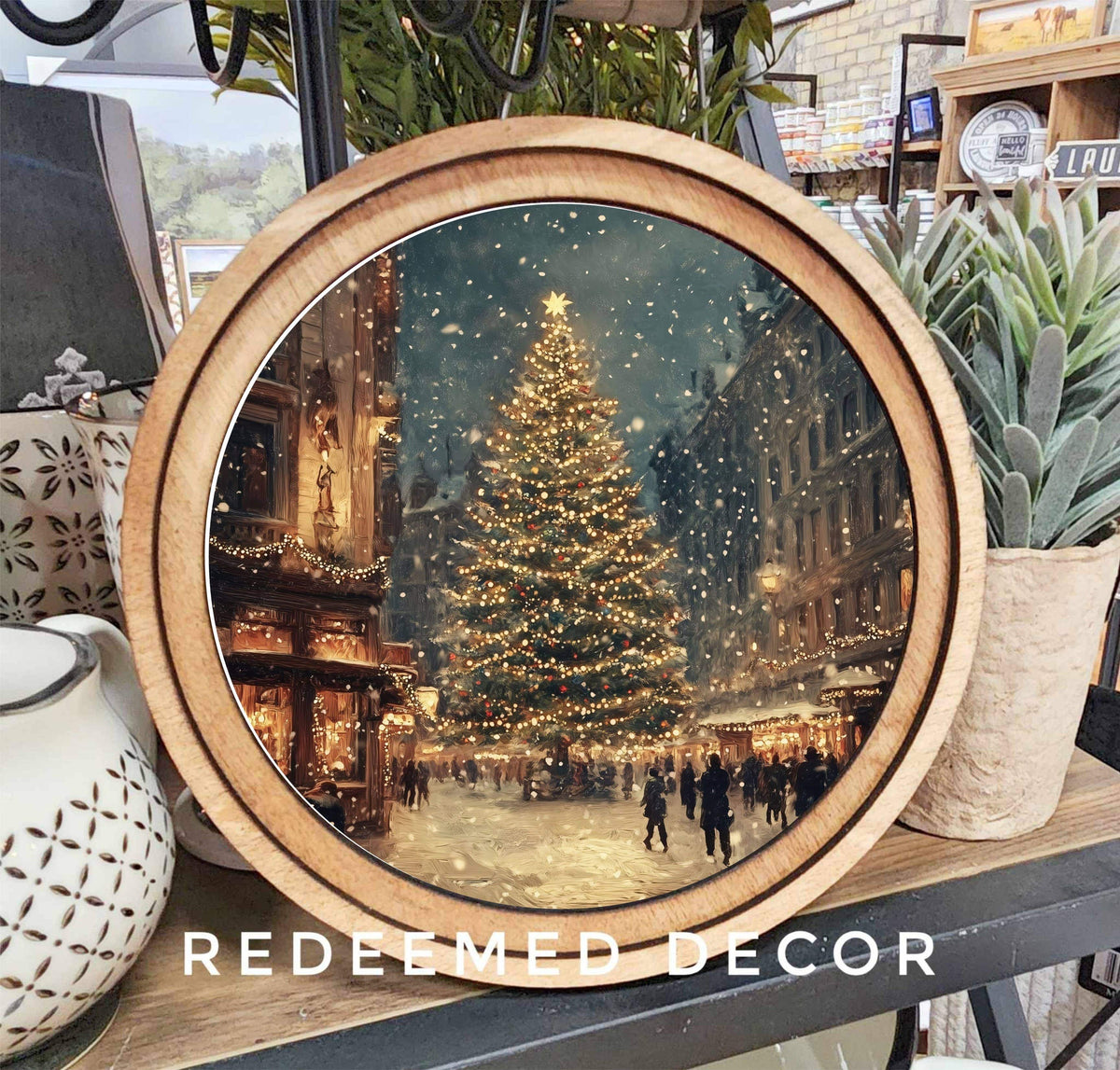 8-inch round wood-framed canvas art depicting a snowy Christmas tree street scene