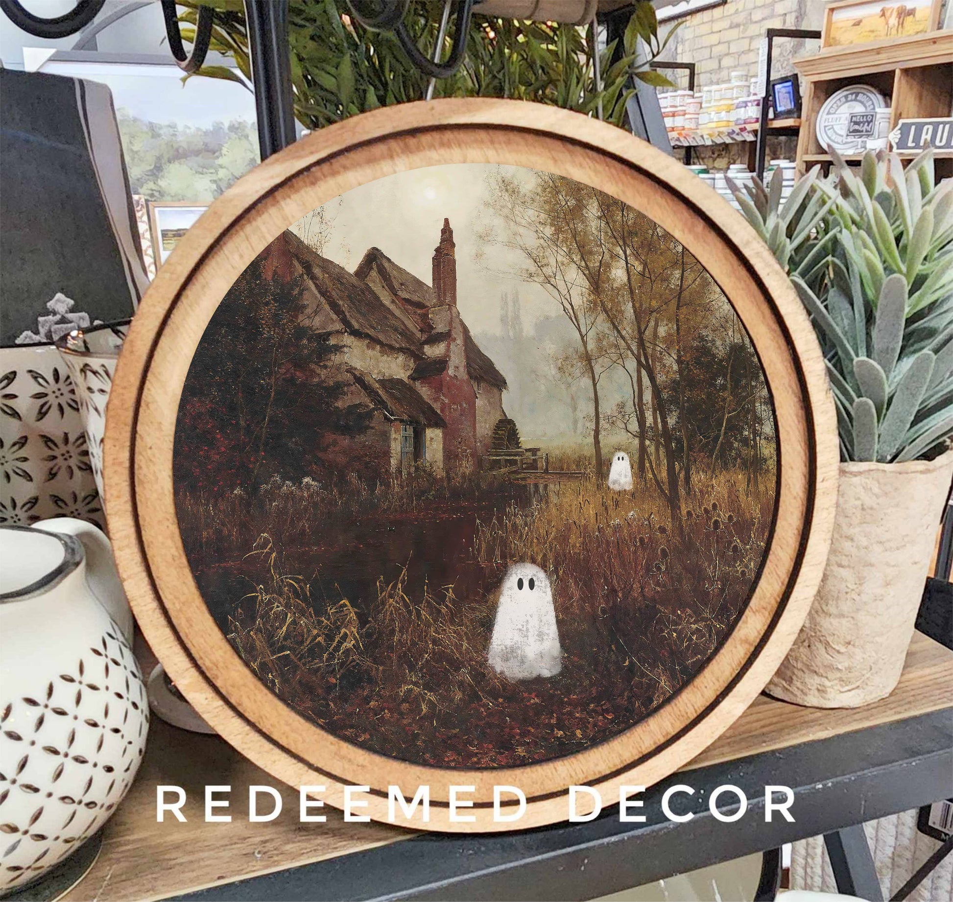Round wood-framed Halloween ghost cottage canvas art with spooky autumn scene