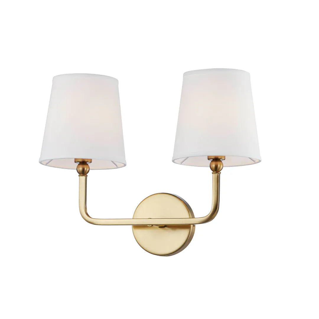 Two-light brass wall sconce with white fabric shades and round backplate
