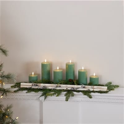 Birch branch bundle centerpiece with green pillar candles and evergreen sprigs