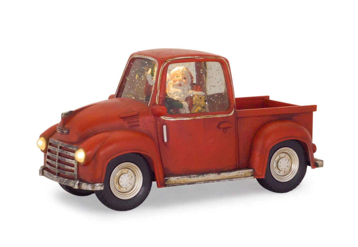 Vintage-style red pickup truck decoration with Santa figurine inside illuminated snow globe cab