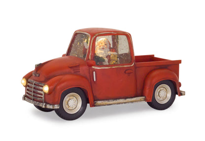 Vintage-style red pickup truck decoration with Santa figurine inside illuminated snow globe cab