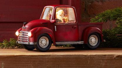 Vintage-style red pickup truck figurine with glowing headlights and illuminated Santa inside cab