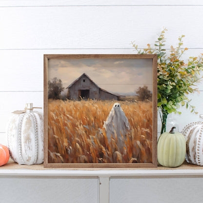 Framed ghost in wheat field painting with decorative pumpkins on shelf