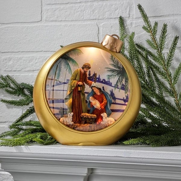 Gold oversized Christmas ornament globe with illuminated Holy Family nativity scene inside