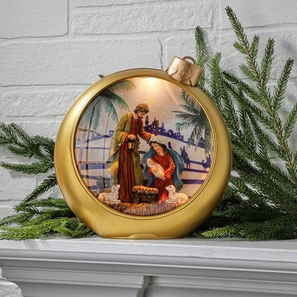 Gold oversized Christmas ornament globe with illuminated Holy Family nativity scene inside