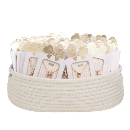 Gold balloon initial letter necklaces on pink striped cards displayed in a white rope basket