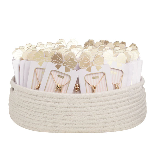 Gold balloon initial letter necklaces on pink striped cards displayed in a white rope basket
