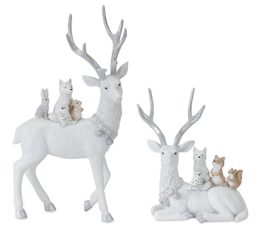 Two white glitter deer figurines with silver antlers and small woodland animal companions on their backs