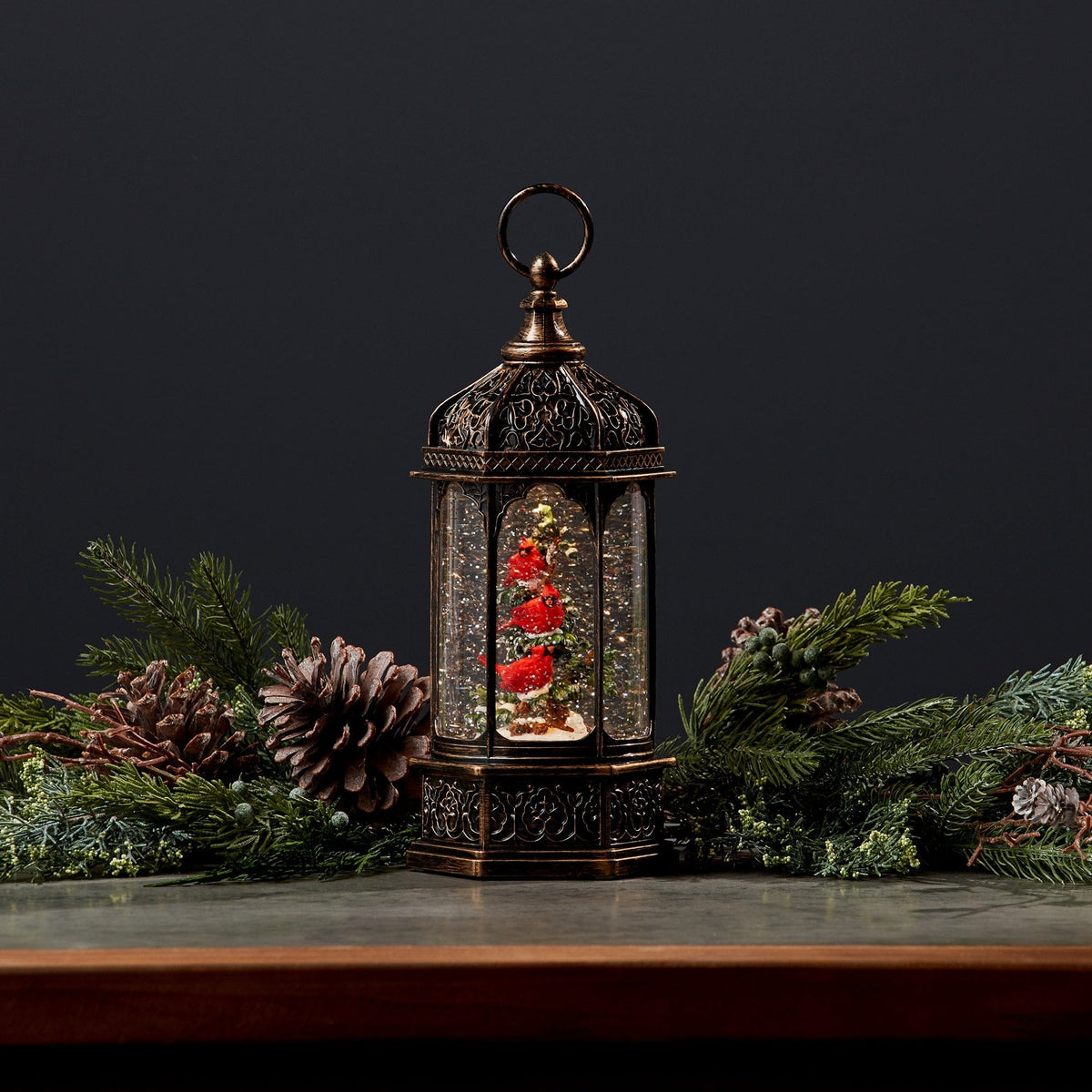 Antique bronze lantern-style snow globe with red cardinal birds on a Christmas tree inside