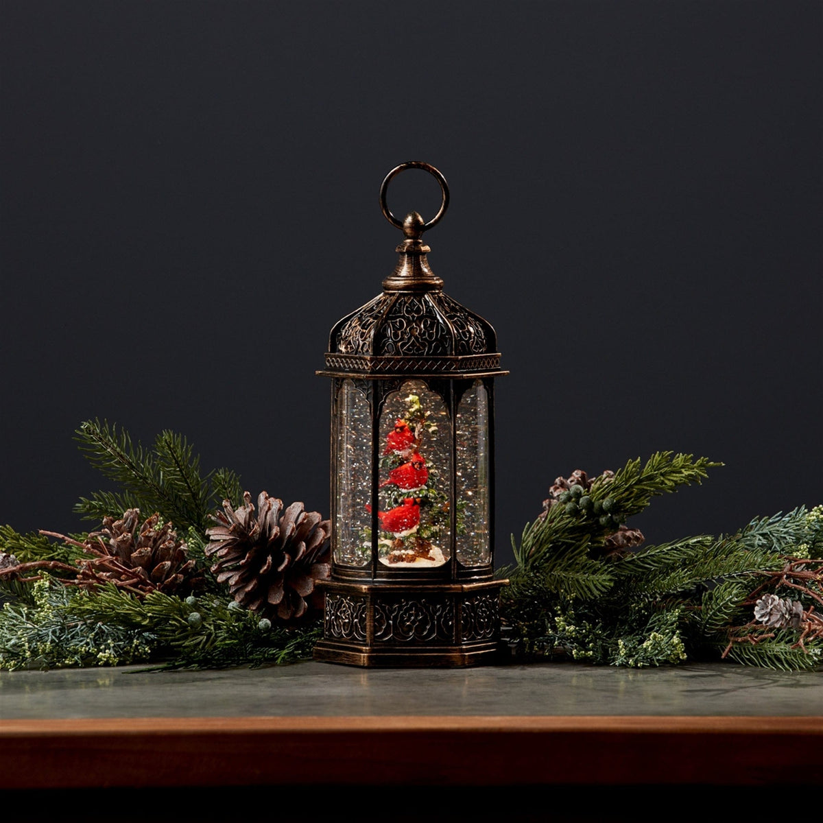 Antique bronze lantern-style snow globe with red cardinal birds on a Christmas tree inside