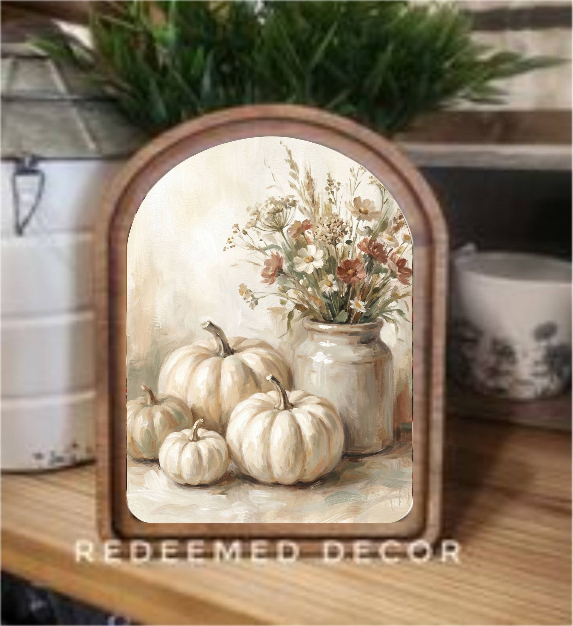 Arched wood-framed canvas art with cream pumpkins and wildflower bouquet in ceramic vase