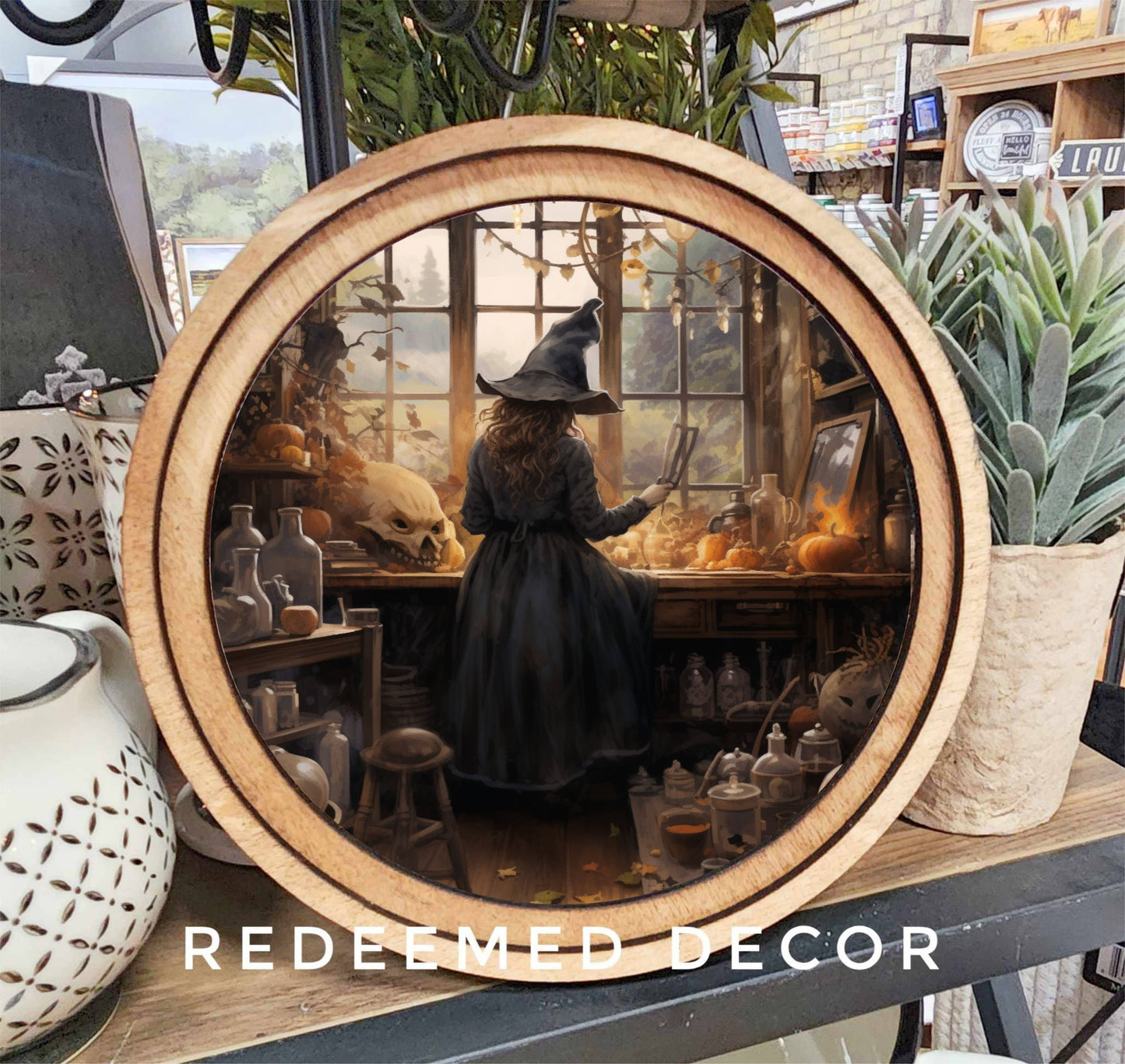 Round wood-framed canvas wall art featuring a witch in her autumn potion workshop