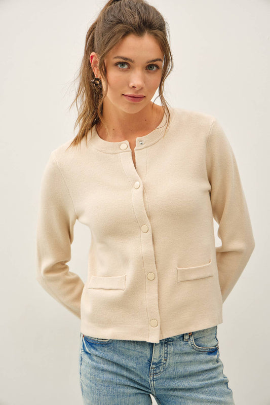 Cream cropped crewneck cardigan with snap buttons and front patch pockets