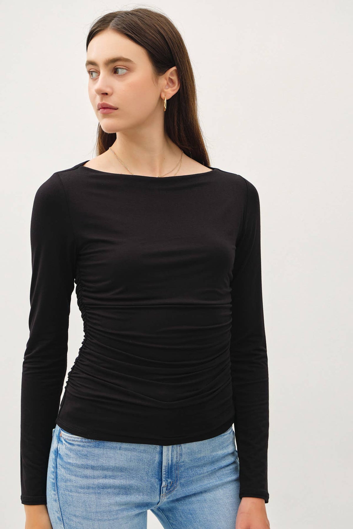 Black long sleeve boat neck top with side ruching, paired with light blue jeans