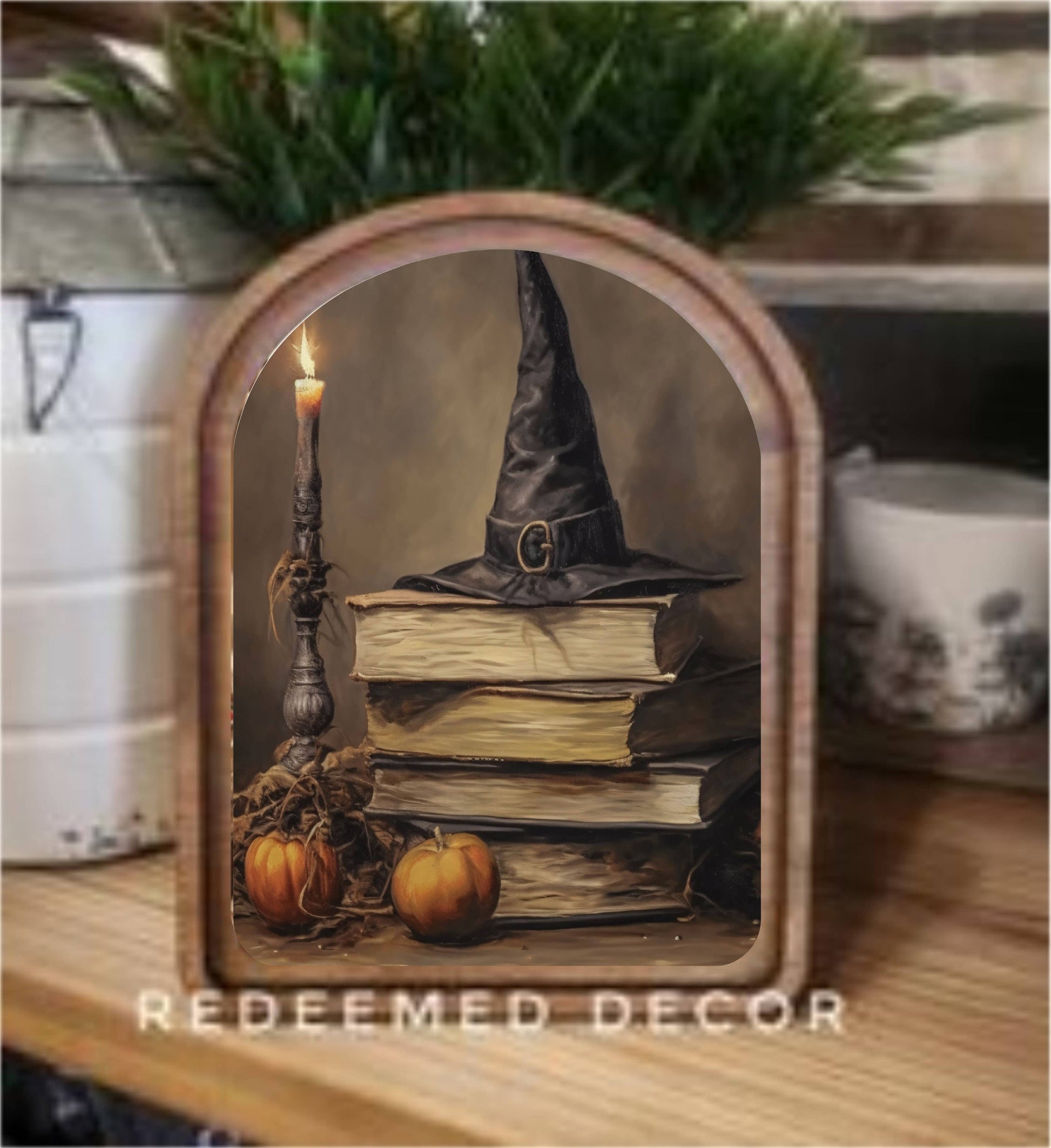 Arched wood-framed Halloween canvas art with witch hat, stacked books, candle, and pumpkins