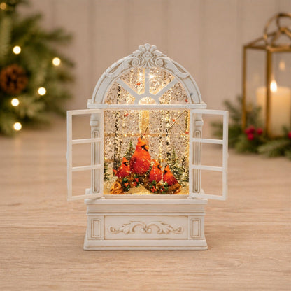 Illuminated snow globe shaped as an arched window with red cardinal birds inside, white ornate frame