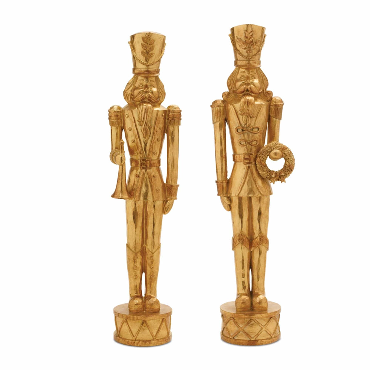 Two gold resin nutcracker soldier figurines holding trumpet and wreath on drum bases