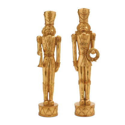 Two gold resin nutcracker soldier figurines holding trumpet and wreath on drum bases