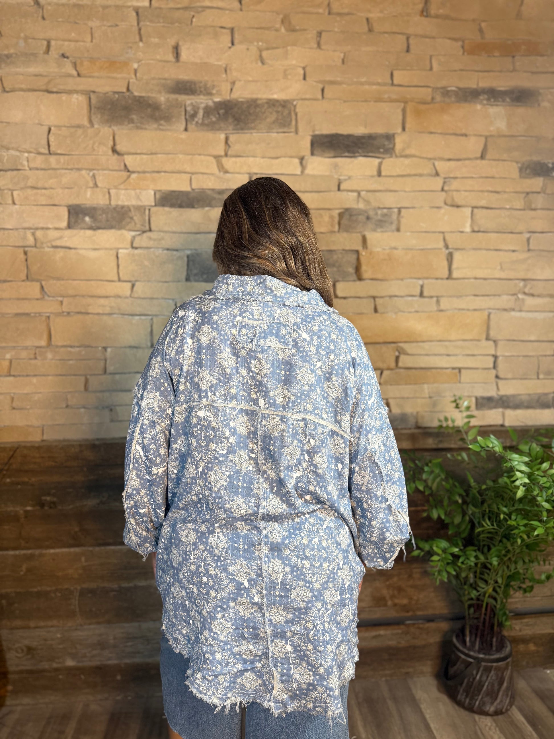 Blue paisley printed button down shirt with frayed hem, back view