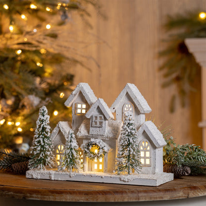 LED-lit white wood village houses with snow-dusted miniature trees on a rectangular base