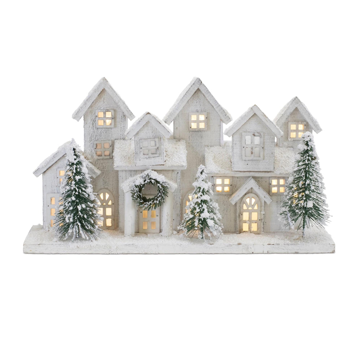 Illuminated white wooden winter village scene with snow-dusted houses and green evergreen trees