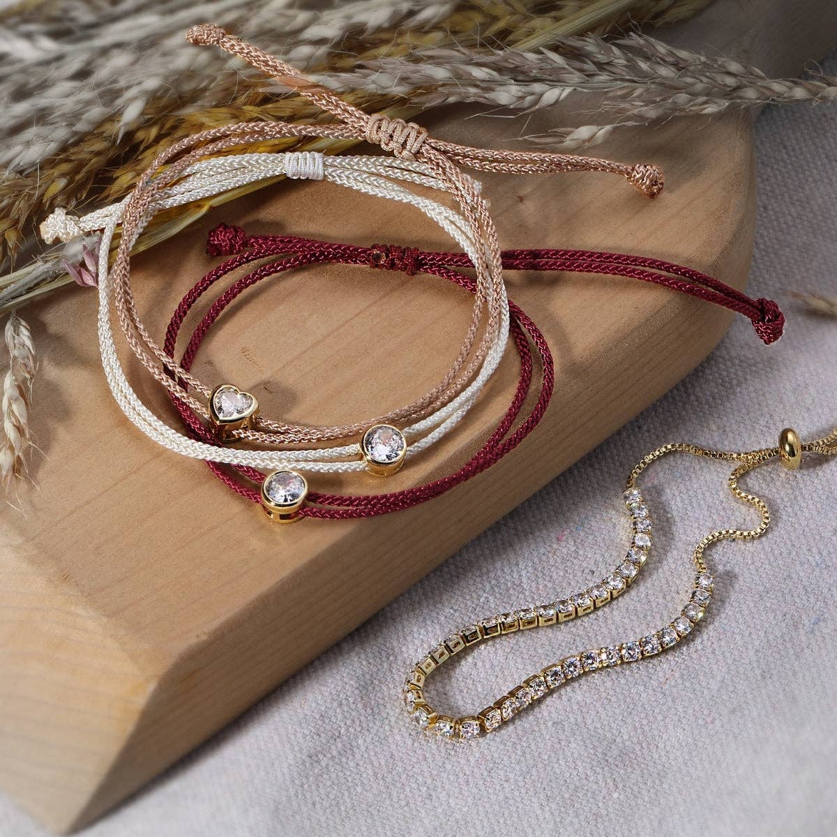 Adjustable braided cord bracelets with gold crystal charms in burgundy, white, and rose gold