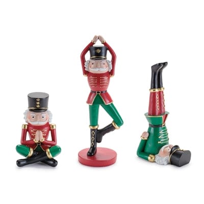 Three nutcracker soldier figurines in red and green performing yoga poses