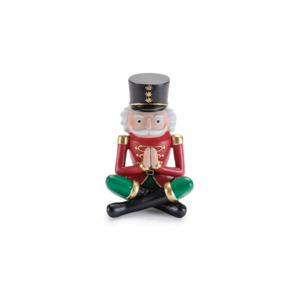 Yoga nutcracker soldier figurine in red jacket, sitting cross-legged in prayer pose