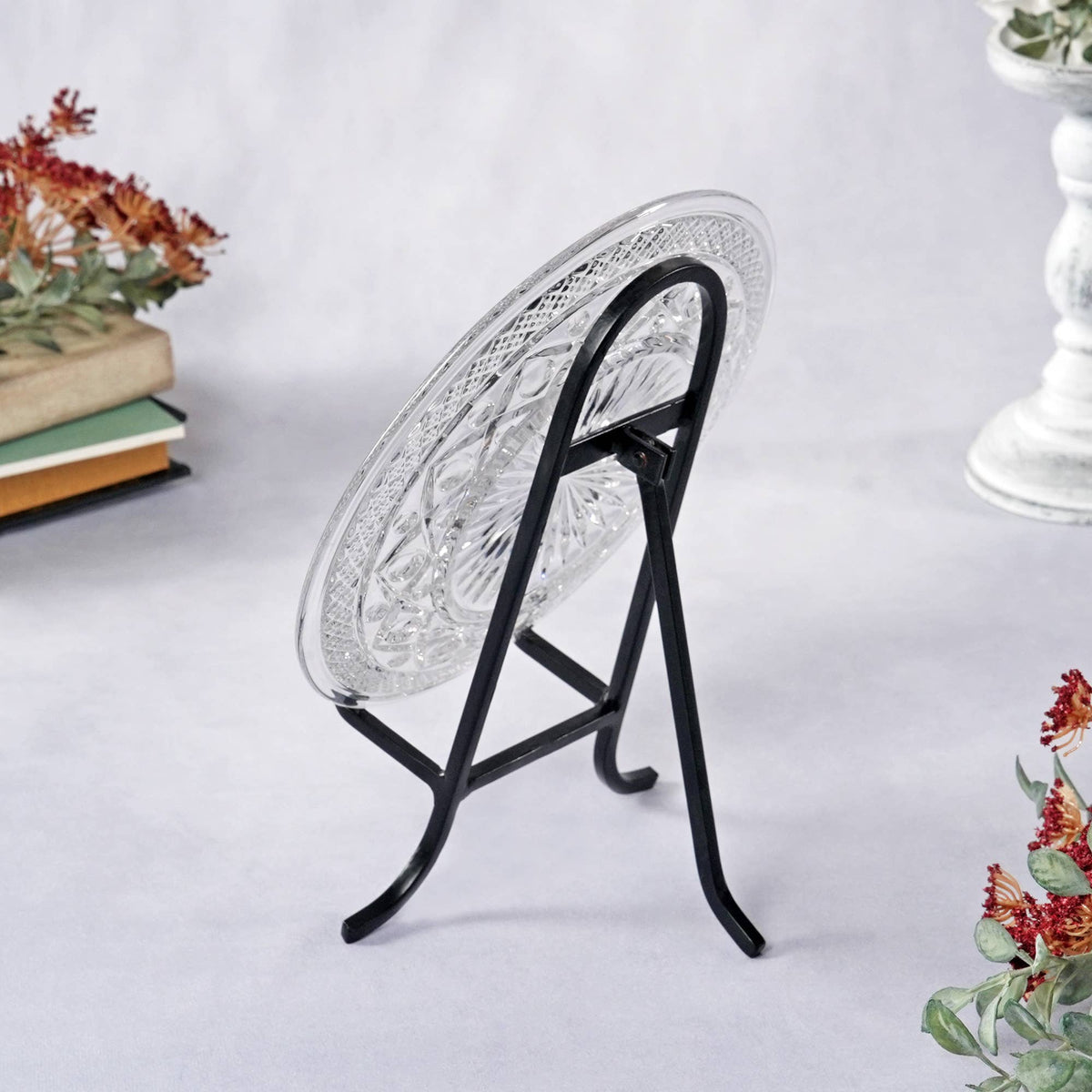 Black wrought iron easel stand displaying a cut crystal glass plate, side view