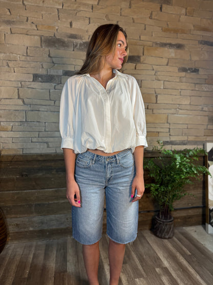 Light wash denim Bermuda shorts with raw hem, 14-inch inseam, worn by model