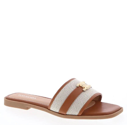 Tan flat slide sandals with canvas strap, gold metal emblem accent