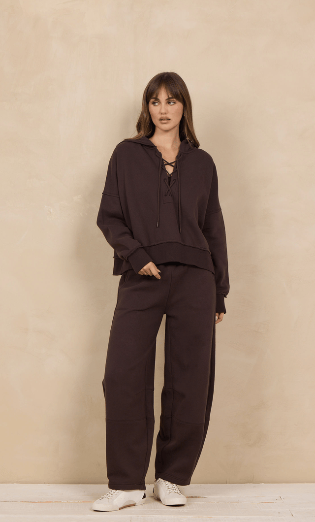 Oversized lace-up hoodie in dark brown worn with matching wide-leg sweatpants, front view