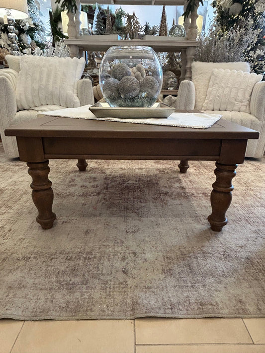 Rustic brown knotty pine wood coffee table with turned legs on vintage rug