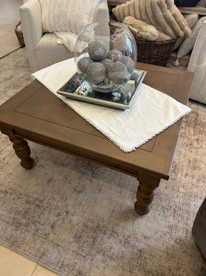 Knotty pine coffee table with turned legs in warm brown finish on gray rug