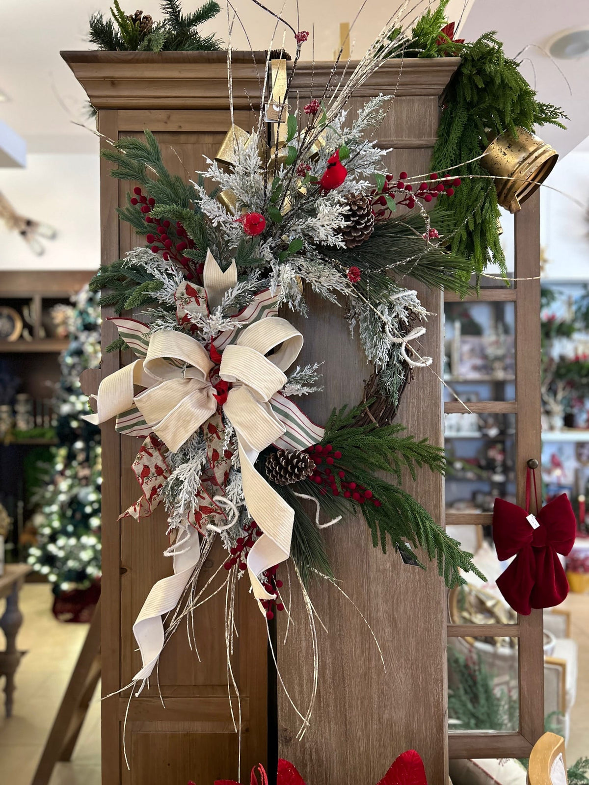 Custom flocked cardinal wreath with cream ribbon, red berries, pinecones, and greenery