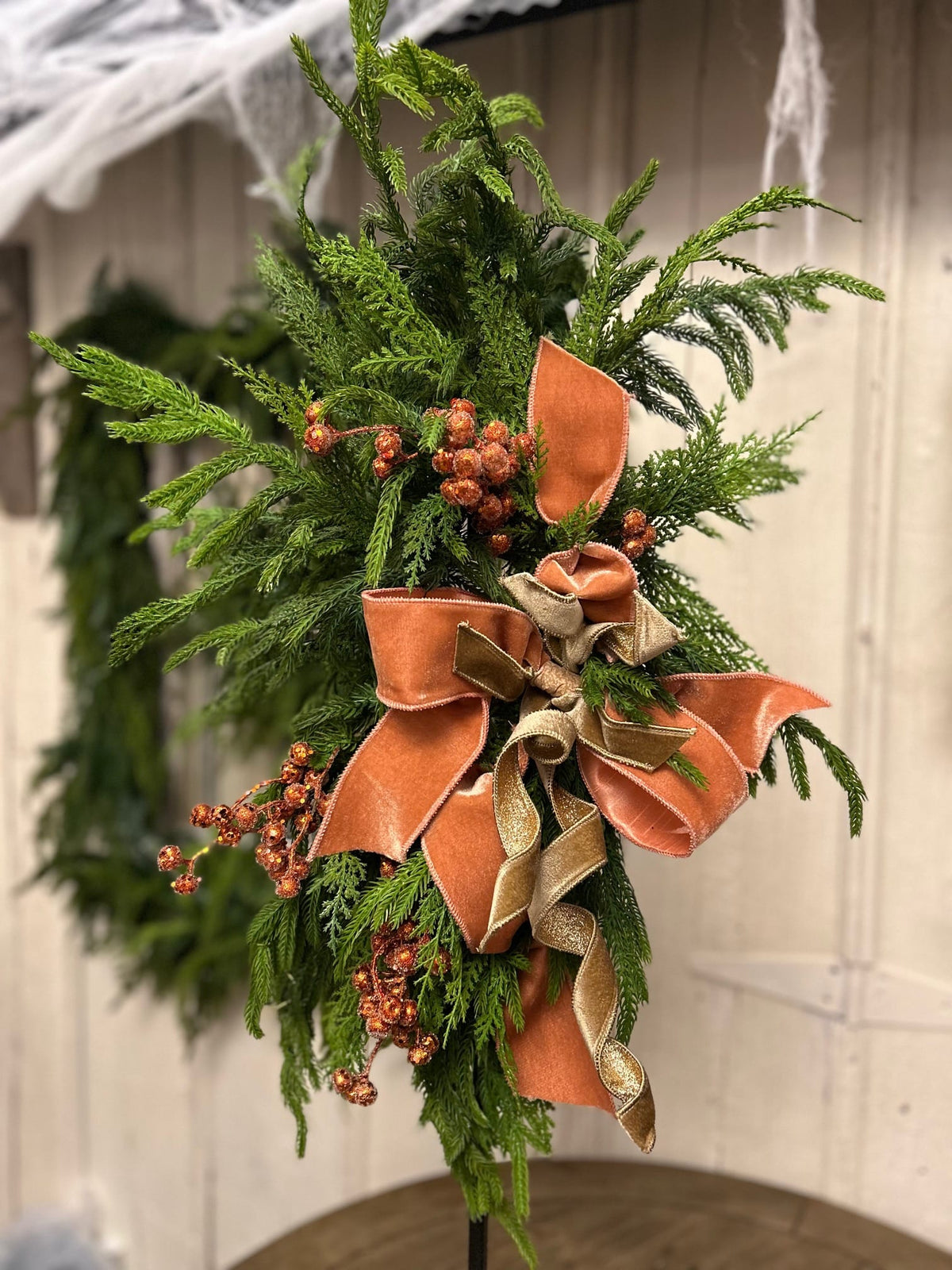 Custom holiday swag with cedar, copper velvet bow, gold ribbon, and berry accents