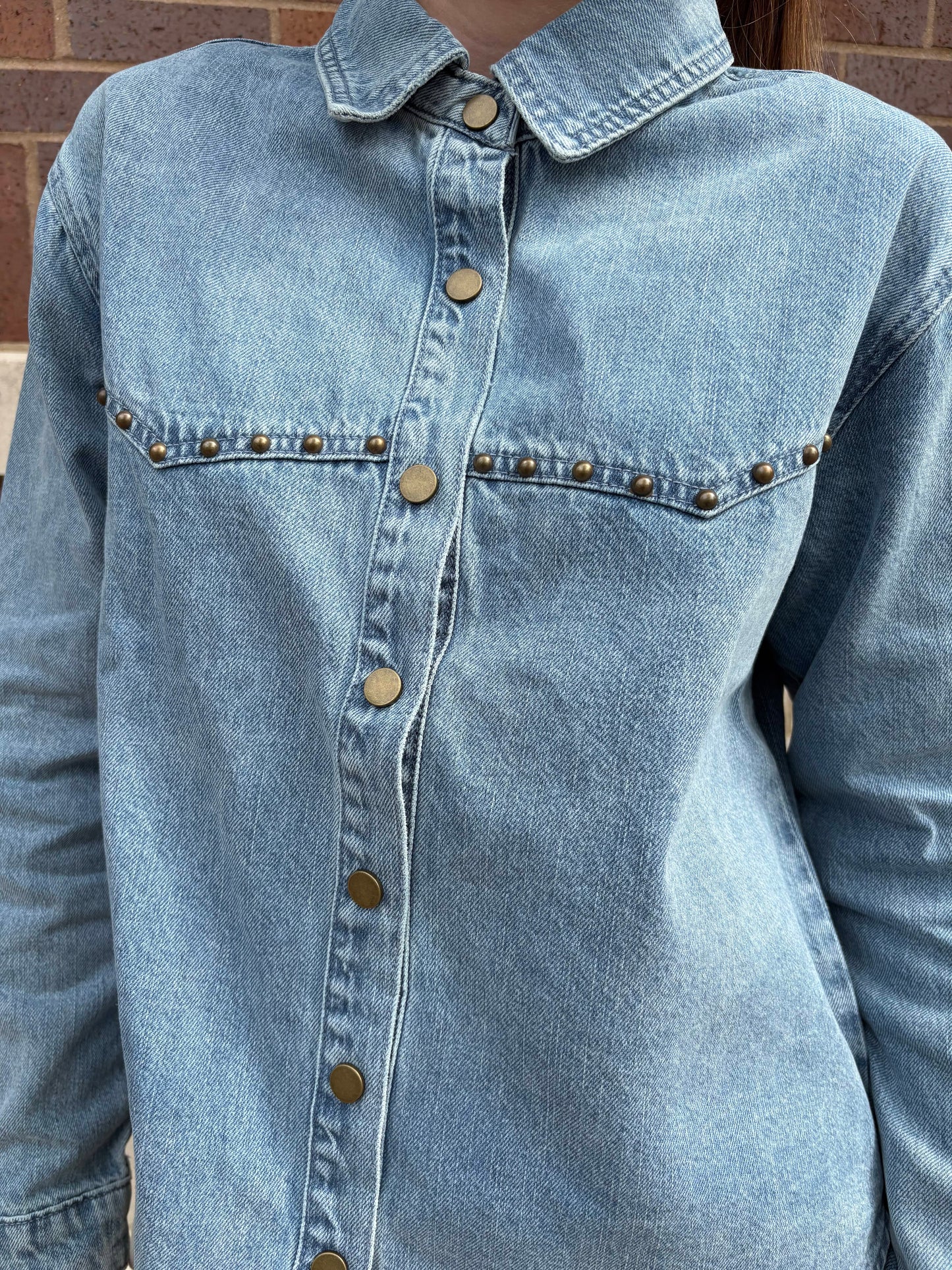 Light wash denim shirt with brass snap buttons and gold stud pocket detail