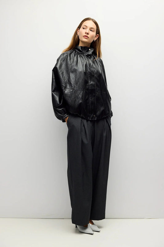 Black oversized faux leather bomber jacket with funnel neck and wide-leg trousers