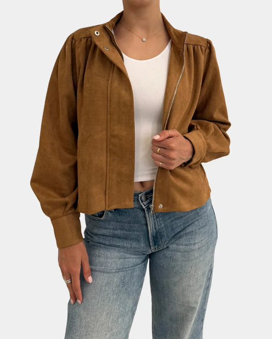 Tan suede mock neck zip-up jacket worn open over white crop top and jeans