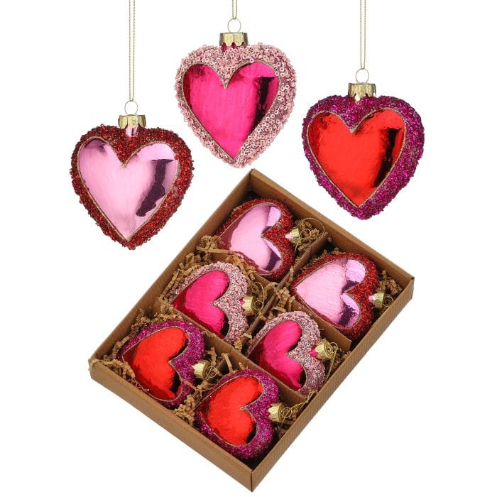 Set of nine glitter and sequin heart-shaped glass ornaments in pink and red, shown boxed and hanging