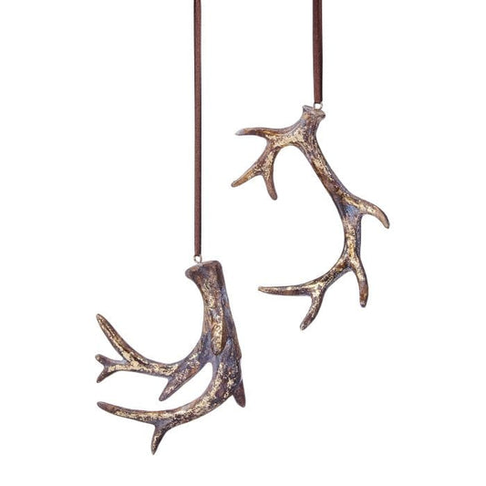 Two resin deer antler ornaments with gold distressed finish hanging from brown leather cords
