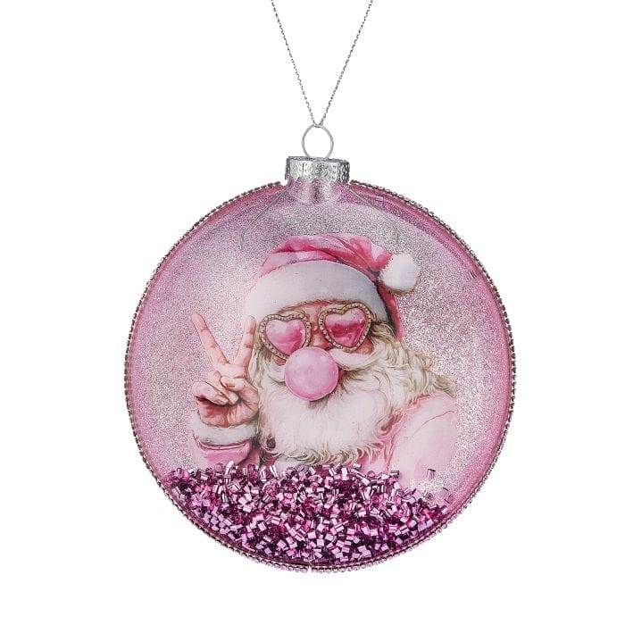 Round glass disk ornament featuring a pink-clad Santa with heart sunglasses blowing a bubble, filled with pink glitter